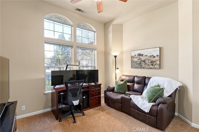 office area featuring a ceiling fan, light colored carpet, visible vents, and baseboards