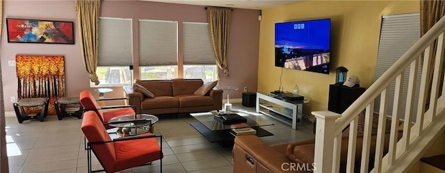 tiled living area featuring baseboards and stairs