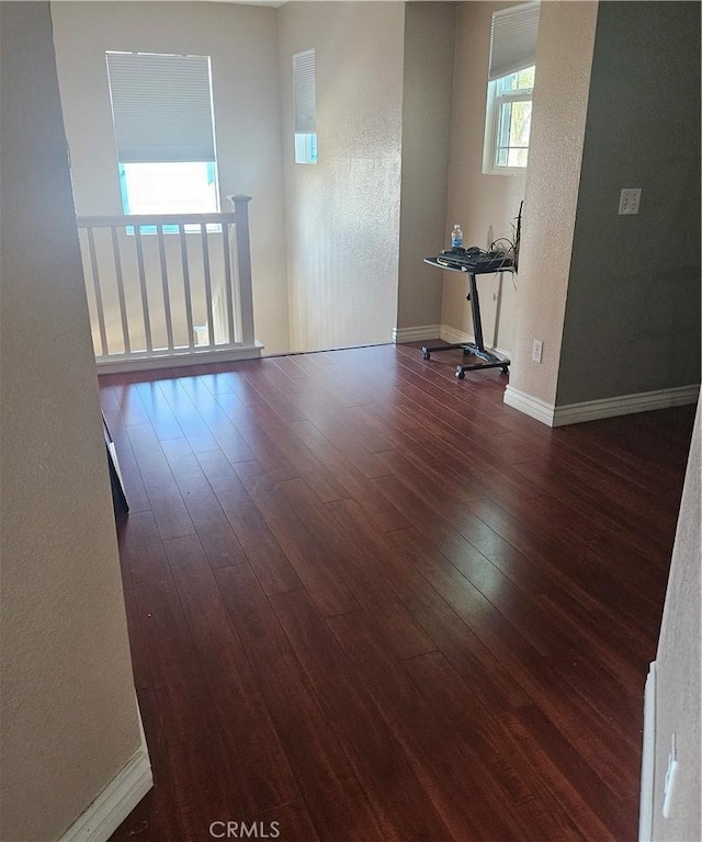 empty room with a textured wall, baseboards, and wood finished floors