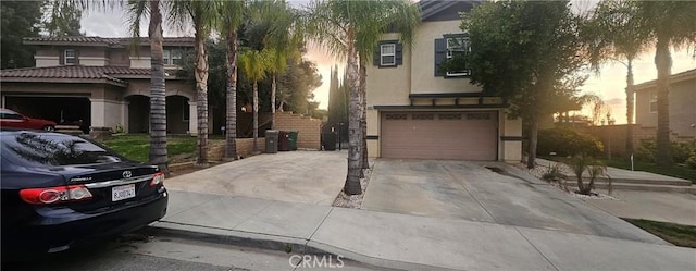 view of front of house with a garage, concrete driveway, and stucco siding