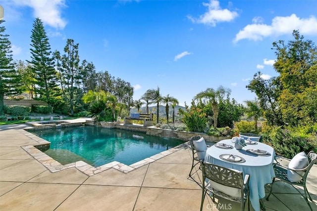 view of swimming pool featuring a pool with connected hot tub, outdoor dining area, and a patio