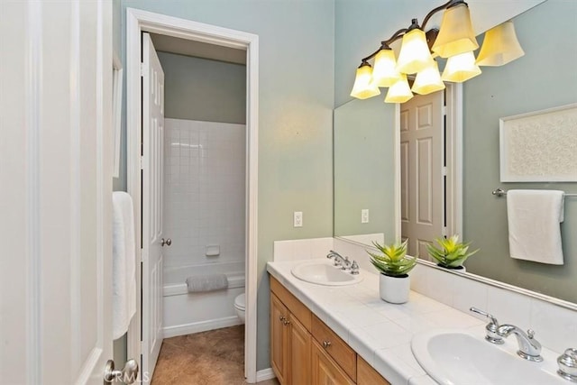 bathroom with double vanity, an inviting chandelier, toilet, and a sink