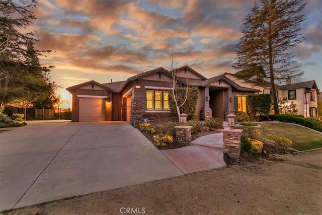 craftsman-style house featuring an attached garage, stone siding, driveway, and fence