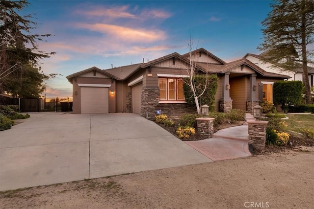 craftsman-style home with a garage, stone siding, fence, and concrete driveway