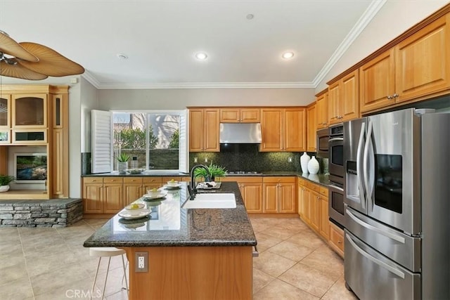 kitchen featuring a kitchen breakfast bar, a kitchen island with sink, stainless steel appliances, under cabinet range hood, and a sink