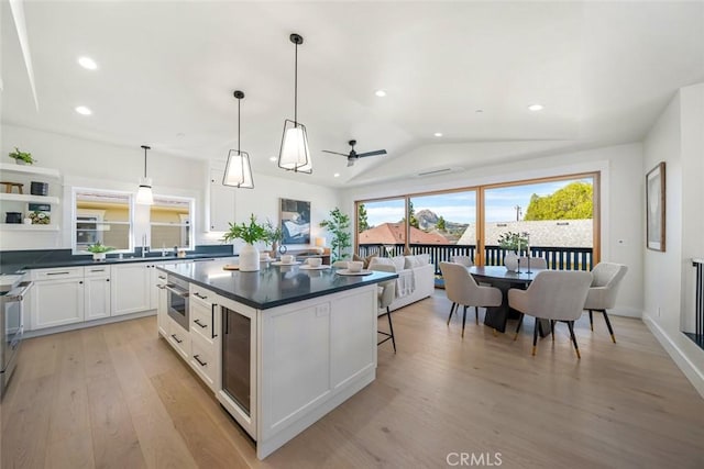 kitchen with decorative light fixtures, lofted ceiling, dark countertops, white cabinets, and beverage cooler