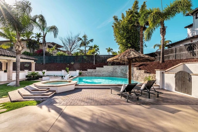 view of swimming pool featuring a patio area, a fenced backyard, and a pool with connected hot tub