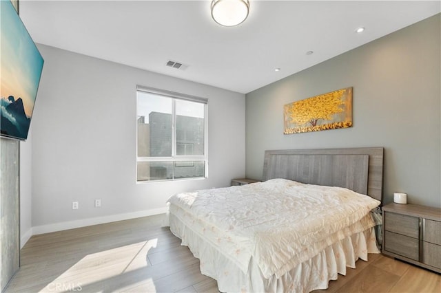 bedroom featuring baseboards, visible vents, and light wood finished floors