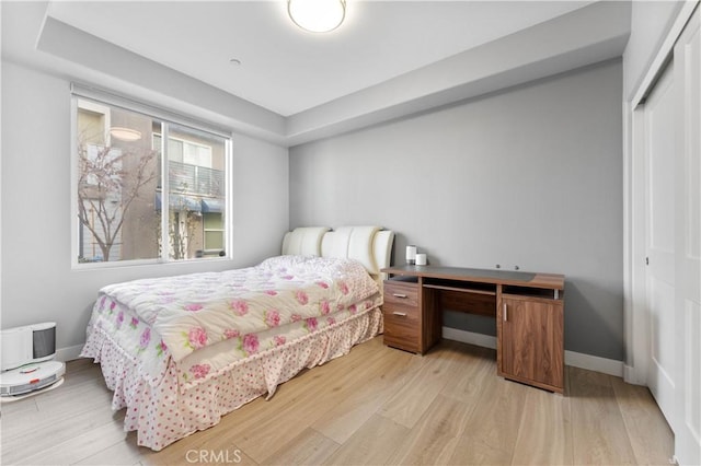 bedroom featuring a closet, baseboards, and light wood finished floors