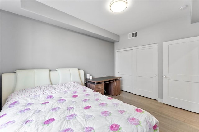 bedroom featuring light wood finished floors, a closet, and visible vents