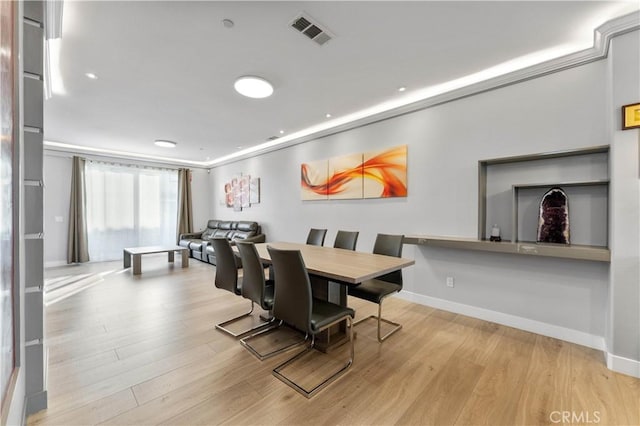 dining room with light wood-style floors, visible vents, and baseboards