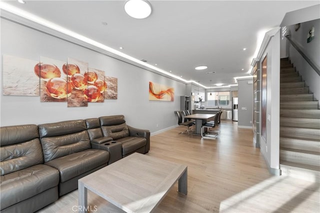 living area featuring light wood-type flooring, baseboards, recessed lighting, and stairs