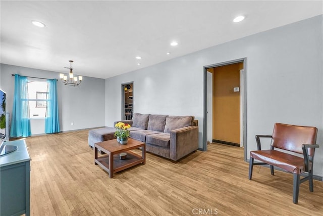 living room with light wood-style flooring, a notable chandelier, and recessed lighting