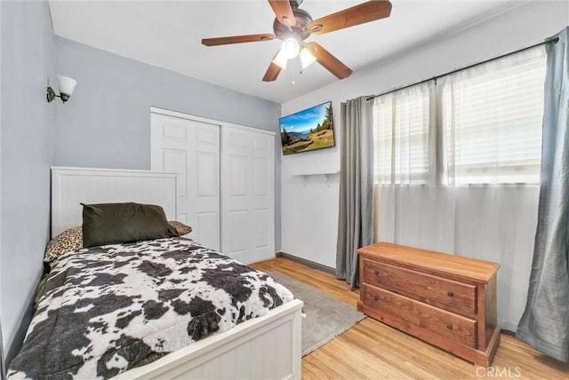 bedroom featuring light wood-style flooring, a ceiling fan, and a closet