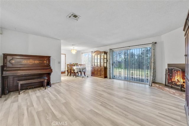 living area with visible vents, light wood-style flooring, and a textured ceiling