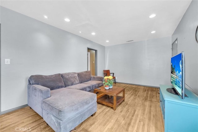 living room with light wood-type flooring, visible vents, baseboards, and recessed lighting