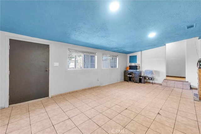 unfurnished living room featuring a textured ceiling, light tile patterned floors, and visible vents