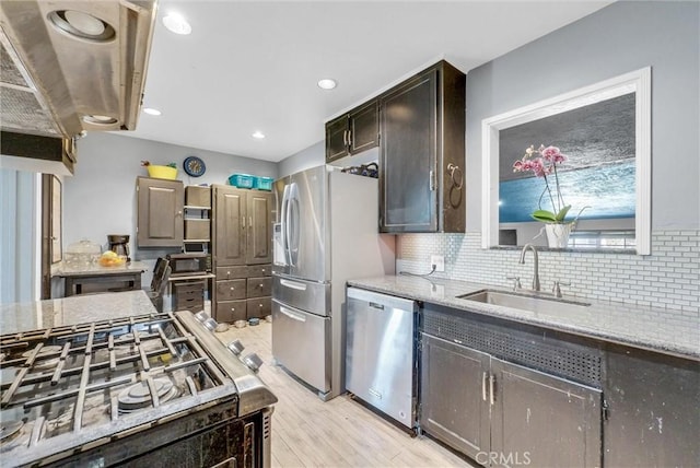 kitchen featuring light wood-style flooring, dark brown cabinetry, stainless steel appliances, a sink, and tasteful backsplash