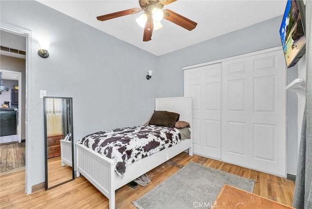 bedroom with a closet, ceiling fan, and light wood finished floors