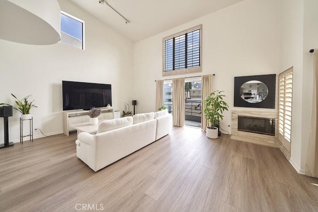1617 S Beverly Glen Blvd Unit 303, Los Angeles, CA 90024 - living area with a high ceiling, a glass covered fireplace, wood finished floors, rail lighting, and baseboards