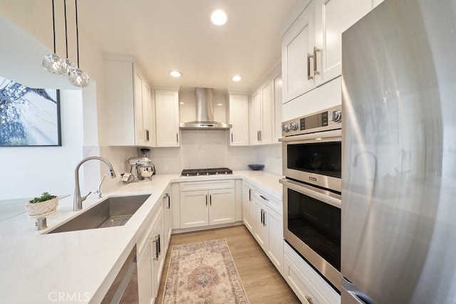 1617 S Beverly Glen Blvd Unit 303, Los Angeles, CA 90024 - kitchen featuring wall chimney range hood, appliances with stainless steel finishes, a sink, white cabinetry, and recessed lighting