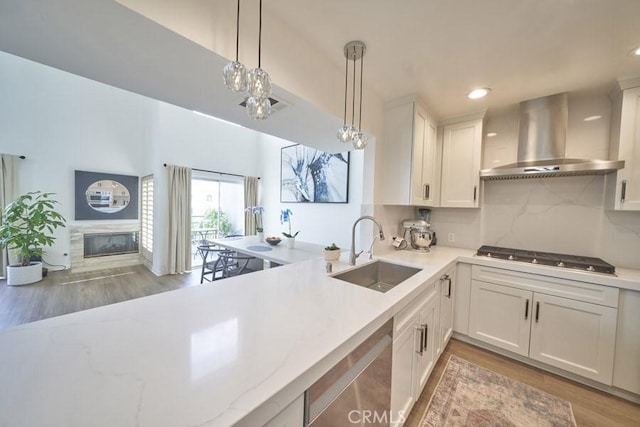 1617 S Beverly Glen Blvd Unit 303, Los Angeles, CA 90024 - kitchen with wall chimney range hood, a sink, stainless steel gas cooktop, light wood-type flooring, and hanging light fixtures