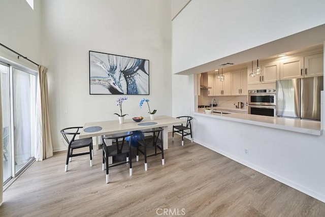 1617 S Beverly Glen Blvd Unit 303, Los Angeles, CA 90024 - dining room with a towering ceiling, light wood-style floors, baseboards, and plenty of natural light