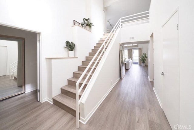 1617 S Beverly Glen Blvd Unit 303, Los Angeles, CA 90024 - stairway featuring wood finished floors, a high ceiling, and baseboards