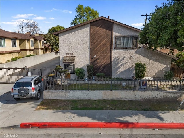 view of side of home with a fenced front yard and stucco siding