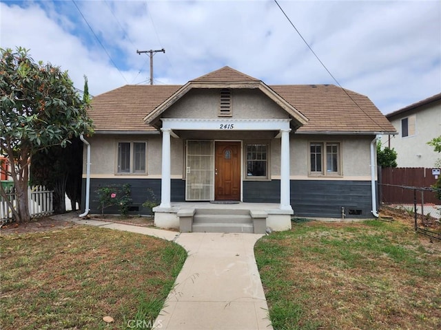 bungalow featuring a front yard, fence, and stucco siding