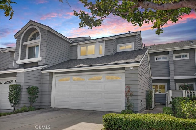 multi unit property featuring a shingled roof and driveway