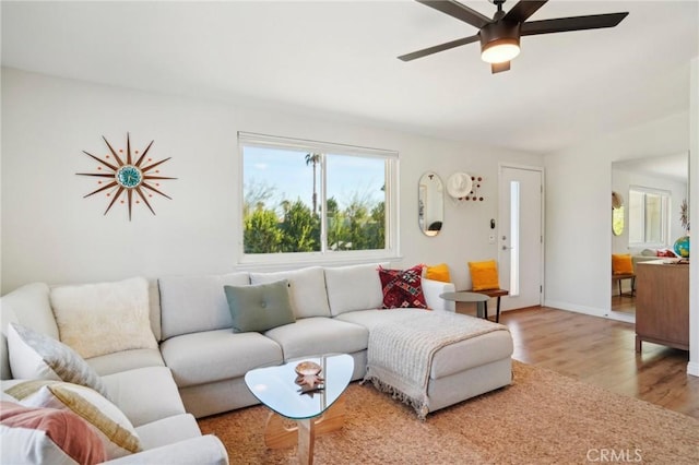 living area featuring light wood-type flooring, ceiling fan, and baseboards