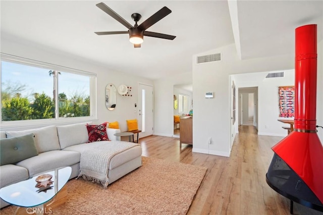 living area with light wood-style floors, baseboards, visible vents, and a ceiling fan