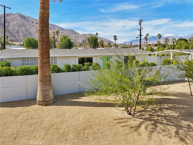 view of front of house featuring fence, a mountain view, and stucco siding