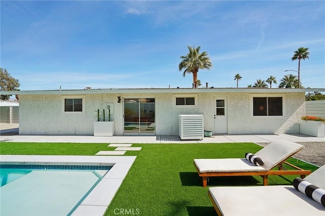 back of property with an outdoor pool, a lawn, a patio, central air condition unit, and stucco siding