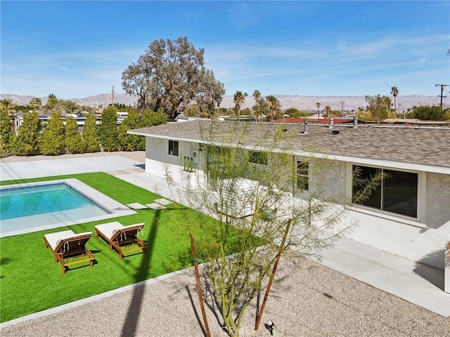 back of property with roof with shingles, a patio, a lawn, a mountain view, and an outdoor pool