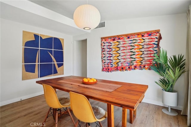 dining area with wood finished floors, visible vents, and baseboards