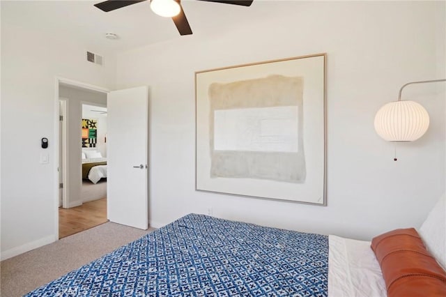 carpeted bedroom featuring baseboards, visible vents, and a ceiling fan