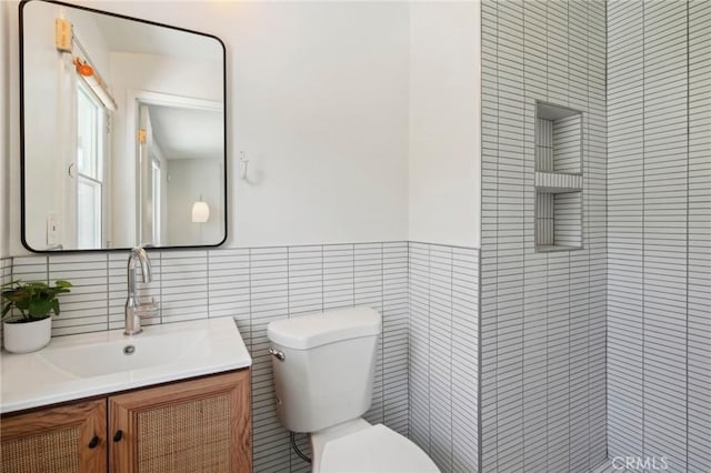 bathroom featuring tile walls, vanity, and toilet