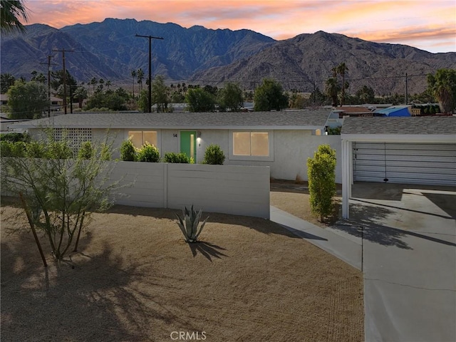 view of front of house with a fenced front yard, an attached garage, a mountain view, concrete driveway, and stucco siding