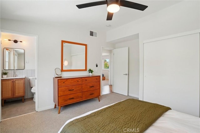 bedroom featuring a closet, visible vents, connected bathroom, and light carpet