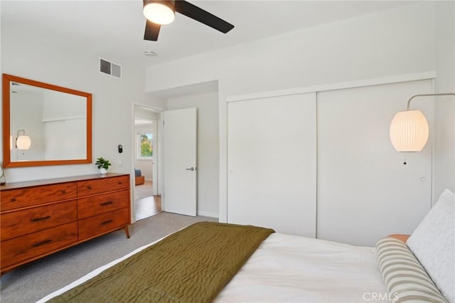 bedroom with a ceiling fan, a closet, visible vents, and light carpet