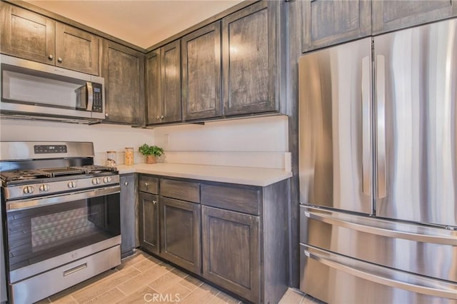 kitchen with wood tiled floor, appliances with stainless steel finishes, light countertops, and dark brown cabinets