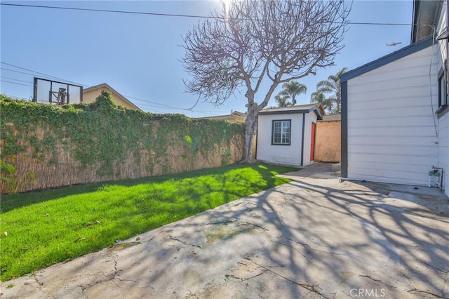 view of yard with an outdoor structure, fence, and a patio