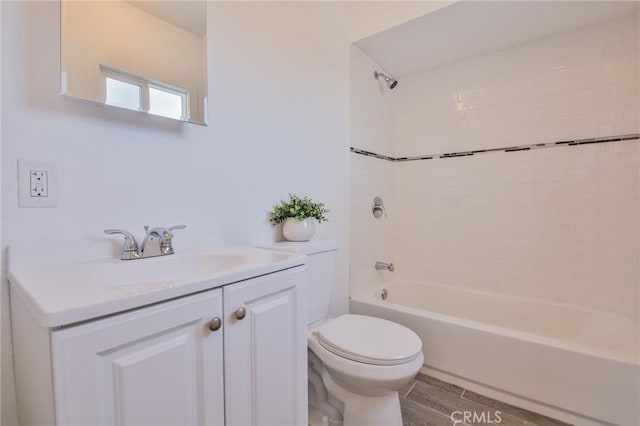 bathroom with toilet, washtub / shower combination, wood finish floors, and vanity