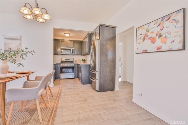 kitchen featuring an inviting chandelier, stainless steel appliances, light countertops, wood finish floors, and pendant lighting