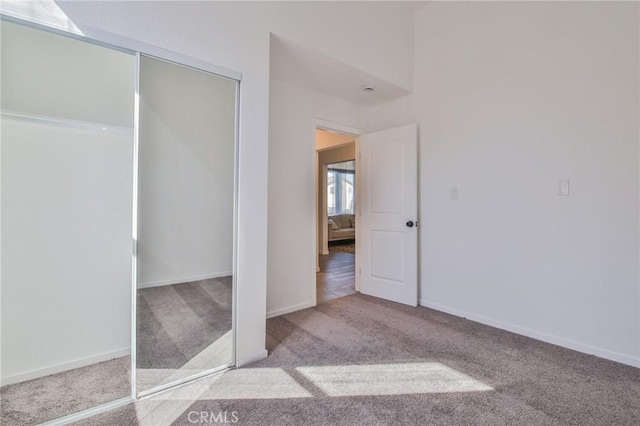 unfurnished bedroom featuring baseboards, a closet, and light colored carpet