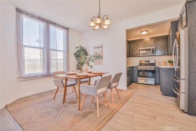 dining room with wood tiled floor, a chandelier, and baseboards