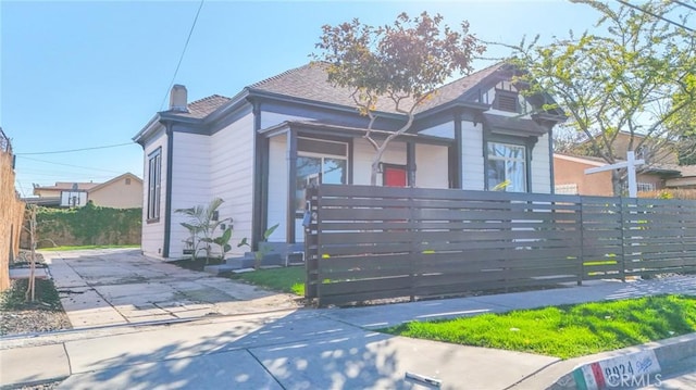 view of front of house featuring a fenced front yard, a chimney, and a gate