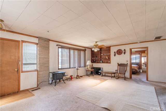 living area with carpet, a wood stove, visible vents, and a healthy amount of sunlight